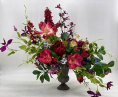 a vase filled with lots of purple and red flowers