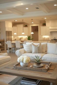 a living room filled with white furniture and lots of pillows on top of a coffee table