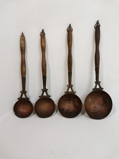 five old fashioned cooking utensils lined up against a white wall