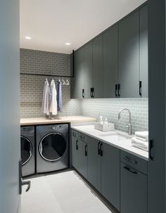 a washer and dryer in a small room with grey cabinets, white flooring