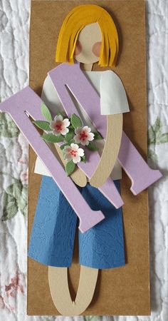 a paper doll is sitting on top of a piece of cardboard with flowers in it