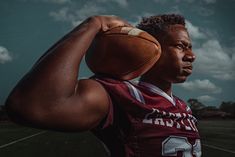 a man holding a football on top of his shoulder