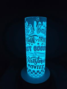 a lit up glass sitting on top of a black table with words written all over it