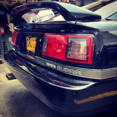 the back end of a black car parked in a parking lot