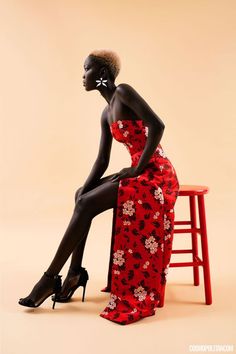 a woman in a red dress sitting on a stool