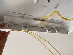 a hand is holding the wires that are connected to an electrical outlet in a ceiling