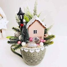 a coffee mug filled with christmas decorations and a house in the middle of it, sitting on top of a table