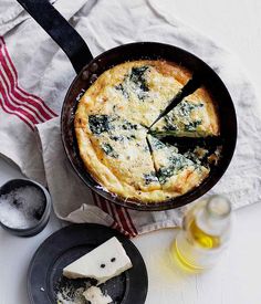 cheese and spinach quiche in a cast iron skillet on a white table