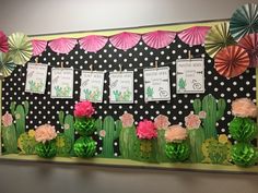 a bulletin board with paper flowers and cactuses on it, hanging from the wall