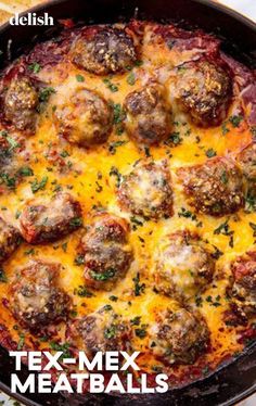 a pan filled with meatballs and cheese on top of a table next to chips