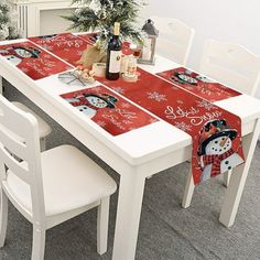 a christmas table runner with snowman and santa clause on it, sitting at a white dining room table