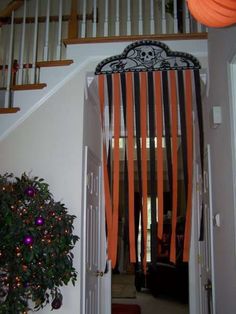 an open door with halloween decorations hanging from it's side and a tree in the doorway