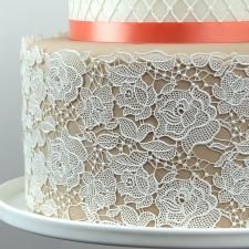 a three layer cake with white lace and an orange ribbon on it's side