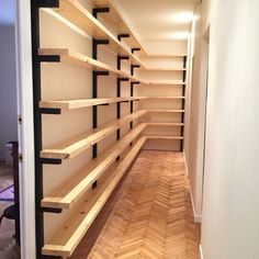 an empty walk in closet with shelving and wood flooring on the side wall