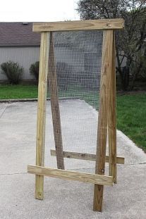 a wooden frame sitting on top of cement next to a grass covered yard with trees