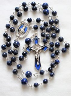 This lapis lazuli rosary can also be worn as a necklace. The body is about 27 inches and the cross extension is 6 inches. The blue enameled cross and connection were made in Italy and are oxidized silver. I used 6mm and 8mm lapis rounds and hand turned each of the wires myself. The crucifix is 1 and 3/4 inches long. This rosary will be slipped into an organza bag and shipped in a bubble mailer. Blue Crucifix Necklace For Spiritual Wear, Blue Crucifix Necklace For Spiritual Purposes, Blue Rosary With 8mm Beads And Crucifix, Blue Rosary With 8mm Beads In Cross Shape, Blue Rosary With 8mm Beads For Healing, Blue Rosary With Round Beads For Healing, Blue Spiritual Rosary With Gemstone Beads, Blue Gemstone Beads Rosary For Spiritual Use, Spiritual Blue Rosary With Gemstone Beads