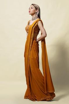 Mustard pre-draped saree with mirror embroidery on the border. Comes with sleeveless blouse and belt.
Component: 3
Pattern: Embroidery
Type Of Work: Mirror, Cutdana, Beads and Thread
Neckline: Scoop
Sleeve Type: Sleeveless
Fabric: Blouse: Silk and Saree: Georgette; Lining: Shantoon
Color: Yellow
Other Details: 
Pre-pleated pallu
Blouse with bead drops
Closure: Side zip
Occasion: Sangeet - Aza Fashions Drape Saree, Yellow Blouse, Blouse Online, Sleeveless Blouse, Silk Blouse, Aza Fashion, Scoop Neck, Blouses For Women, Types Of Sleeves