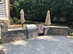 an outdoor kitchen with grill and umbrellas