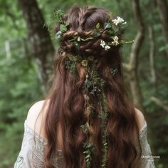 a woman with long brown hair and flowers in her hair is standing in the woods