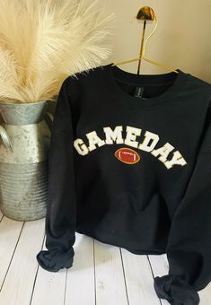 Experience the ultimate fusion of style, comfort, and team spirit with our Gameday Sweatshirts. Customizable to your favorite team and crafted using Gildan's elite crewneck sweatshirts, our sweatshirts are an essential addition to your wardrobe. The chenille letter patches add a chic vibe, making you stand out in the crowd. Show off your team pride in a fashion-forward way with our Gameday Sweatshirts. Let the games begin! Black Sweatshirt For Game Day Sports Season, Black Sweatshirt For Game Day, Black School Spirit Sweatshirt With Crew Neck, Black Sweatshirt For Cheerleading In Fall, Black Team Spirit Sweatshirt For Fall, Black Team Spirit Sweatshirt For College, Collegiate Crew Top For Game Day, Sporty Letter Print Sweatshirt For Game Day, Sporty Sweatshirt With Letter Print For Game Day