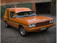 an orange car parked in front of a brick building