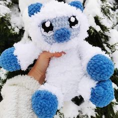 a hand holding a stuffed animal in the snow