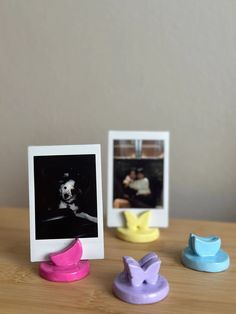 three different colored photo frames sitting on top of a wooden table