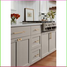 a kitchen with white cabinets and gold handles