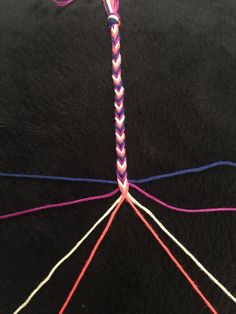 a close up of some colorful yarn on a black surface with an odd shaped object in the middle