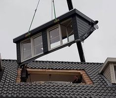 a man is working on the roof of a house with a crane attached to it