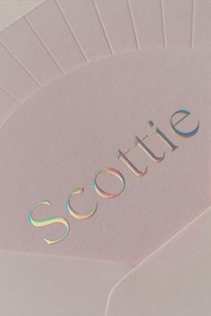 the word scottie is placed on top of several sheets of paper with holographics