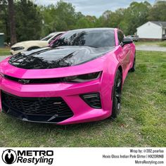 a pink chevrolet camaro is parked in the grass