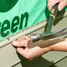 a person holding a pair of pliers in front of a green sign with the word green on it