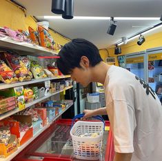 a young man pushing a shopping cart through a grocery store filled with food and drinks