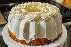 a cake with white frosting sitting on top of a table next to a stove