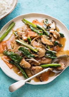 a white plate topped with mushrooms, asparagus and carrots next to rice