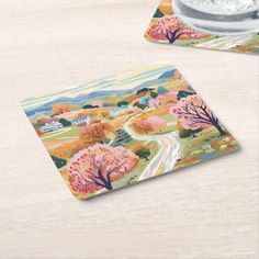 two coasters with an image of a country road and trees on them, sitting on a table