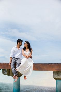 a man and woman are sitting on a pier