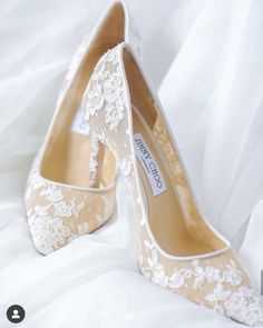 a pair of wedding shoes sitting on top of a white bed covered in sheets and lace