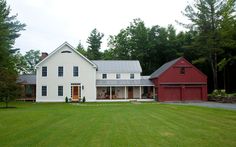 a large white house sitting in the middle of a lush green field next to trees