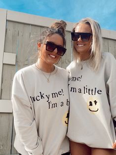 two women standing next to each other wearing matching sweatshirts