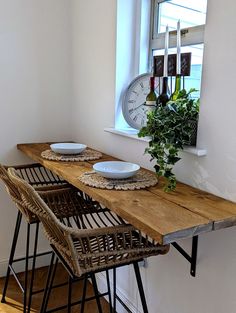 a wooden table topped with two white plates next to a window