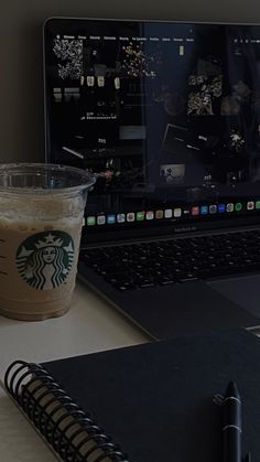 a laptop computer sitting on top of a desk next to a cup of starbucks coffee