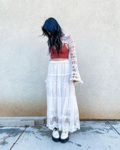 a woman standing in front of a wall with her back to the camera and wearing white shoes