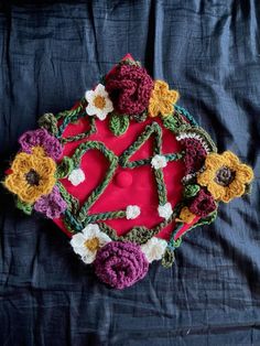 a crocheted doily with sunflowers and flowers on it sitting on a blue cloth