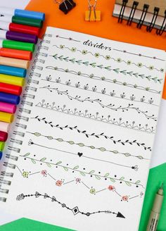 an open notebook with various hand drawn designs on it next to crayons and markers