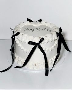 a white cake with black ribbon and happy birthday written on it