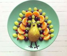 a plate that has fruit on it with a turkey made out of grapes and oranges