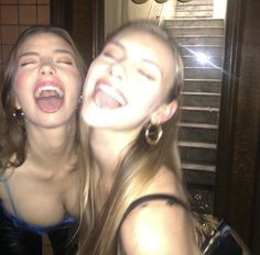 two young women are laughing and posing for the camera with their mouths open in front of them