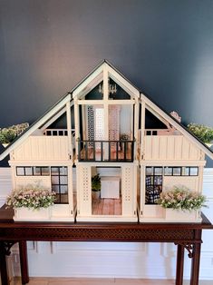 a doll house is on top of a table with flowers in the window boxes and potted plants